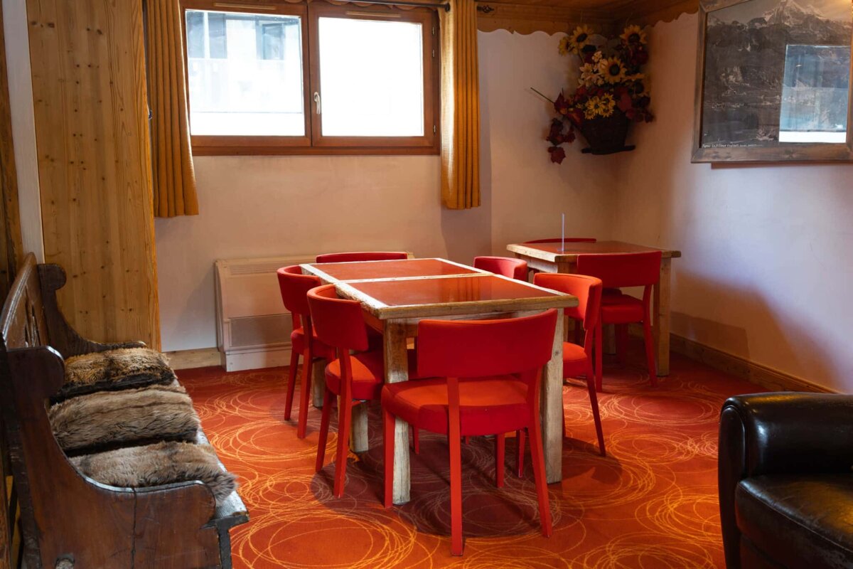 A room with red chairs and tables and a window