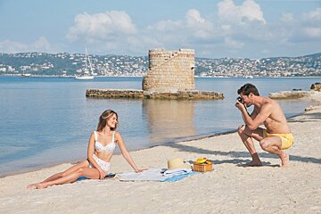 A man taking a picture of a woman on the beach