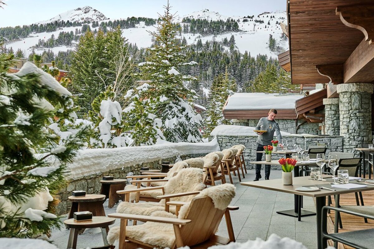 A man standing in front of a restaurant with a mountain in the background