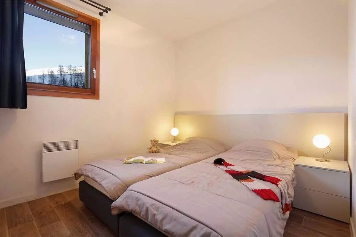 A bedroom with two twin beds and a window