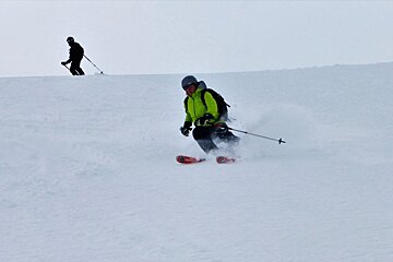 a man skiing in a green jacket