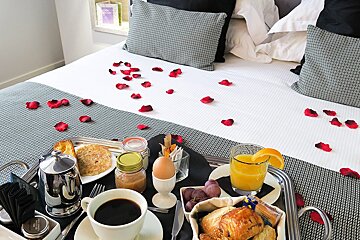 A tray of food on a bed with rose petals on it