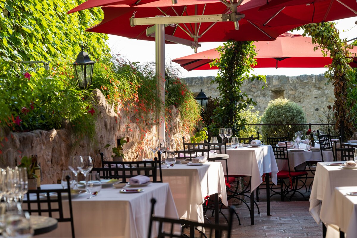 A restaurant with tables and chairs under red umbrellas