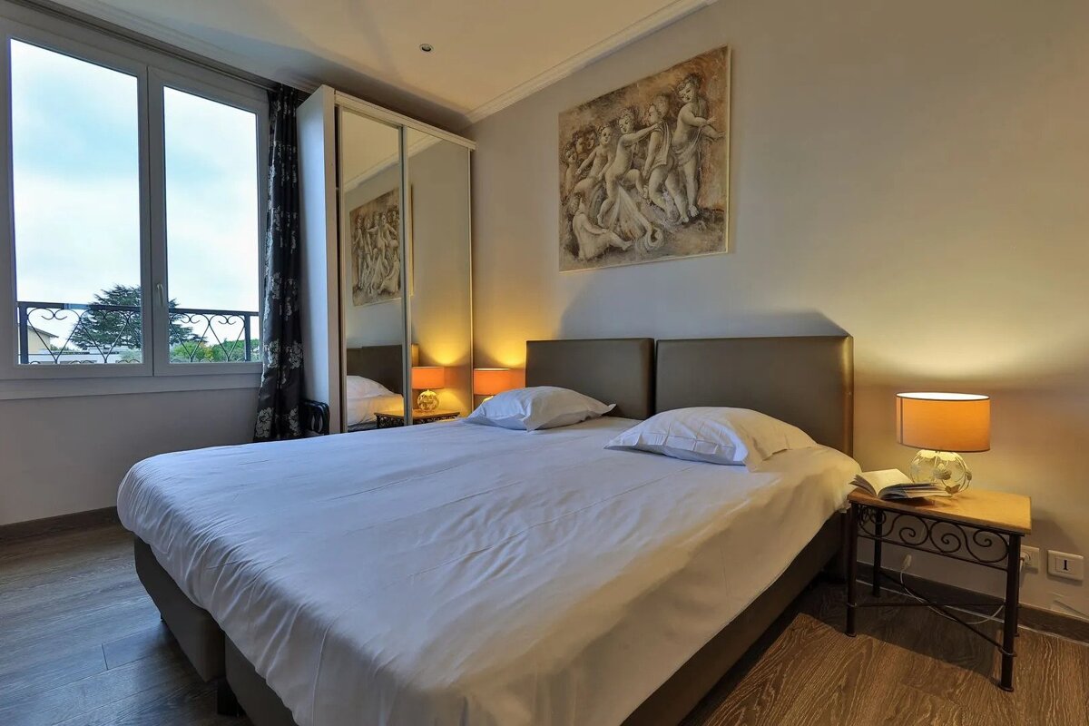 A bedroom with two beds and a painting on the wall