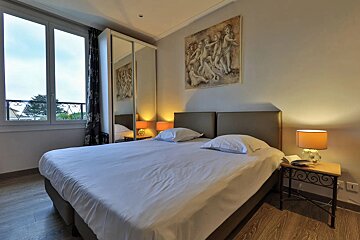 A bedroom with two beds and a painting on the wall