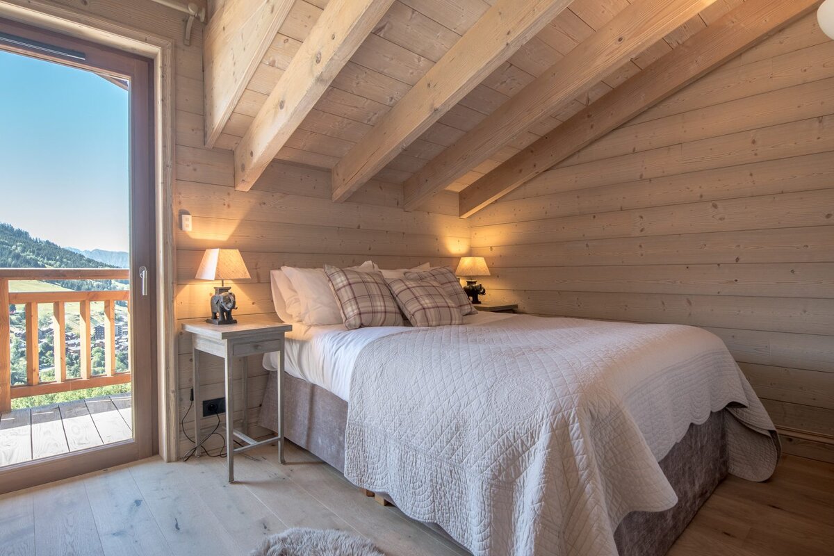 A bedroom in a log cabin with a bed and two lamps