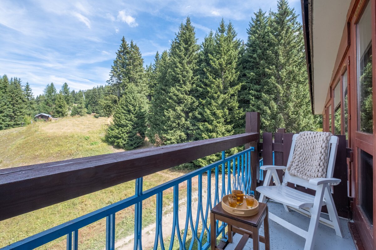 A rocking chair sits on a balcony overlooking a forest