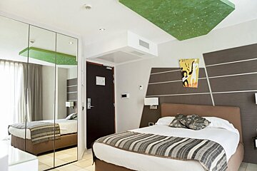 A hotel room with a bed and a painting on the wall