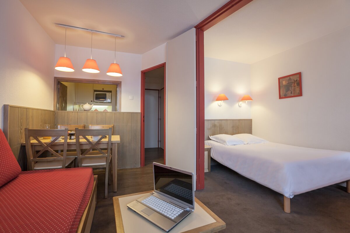 A laptop sits on a table in a hotel room