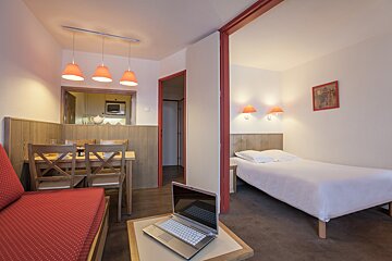 A laptop sits on a table in a hotel room