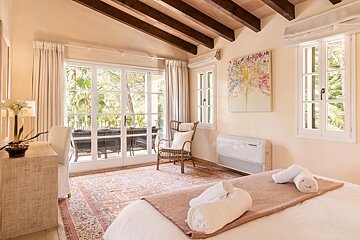 A bedroom with a painting on the wall above the bed
