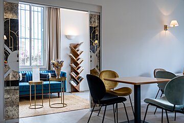 A living room with a blue couch and tables and chairs