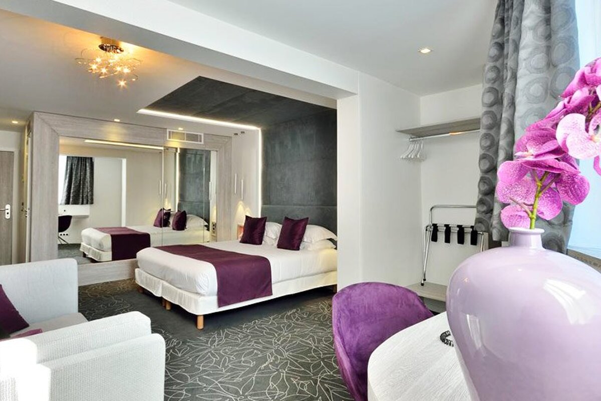 A hotel room with a purple vase of flowers