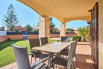 A table and chairs on a patio with a basketball hoop in the background