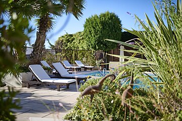A swimming pool surrounded by chairs and palm trees