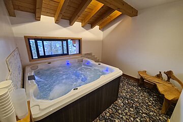 A hot tub in a room with a wooden bench