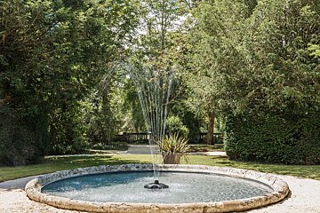 A fountain in a garden with trees in the background