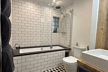A bathroom with white tiles and a black and white checkered floor