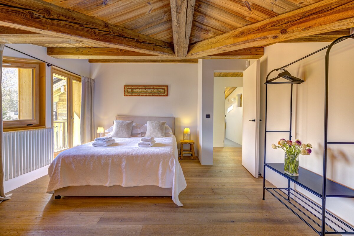 A bedroom with a wooden ceiling and a large bed