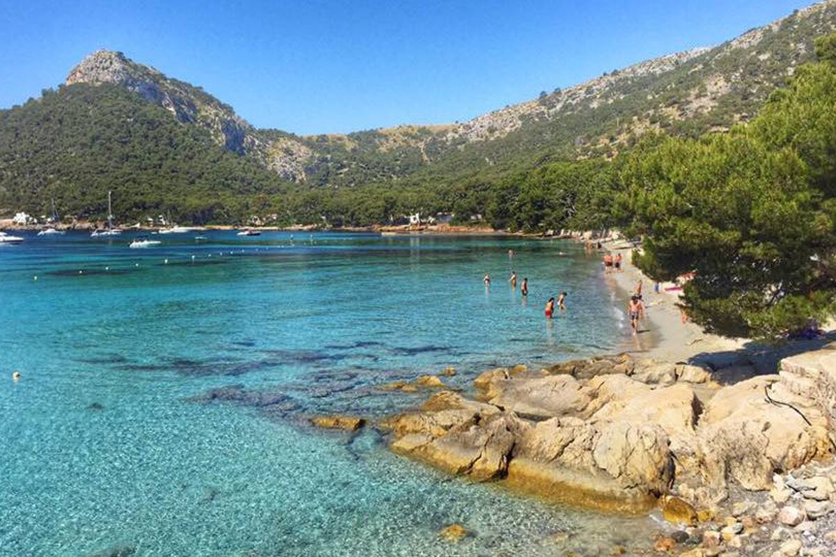 people swimming in the sea at a beach in mallorca