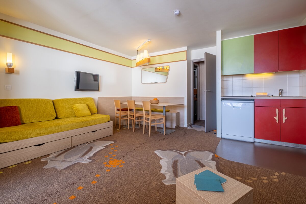 A living room with a yellow couch and red cabinets