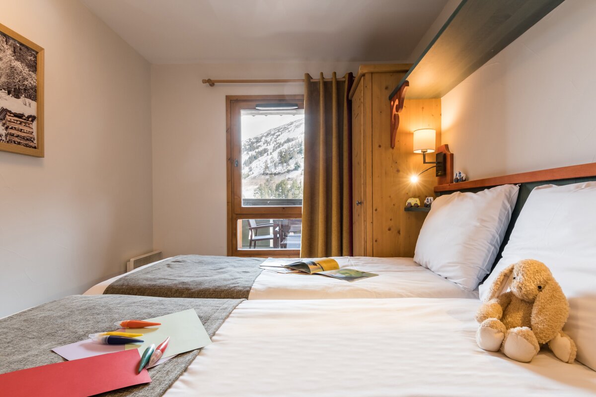 A bedroom with two beds and a teddy bear on the bed