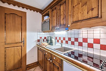 A kitchen with wooden cabinets and red and white tiles