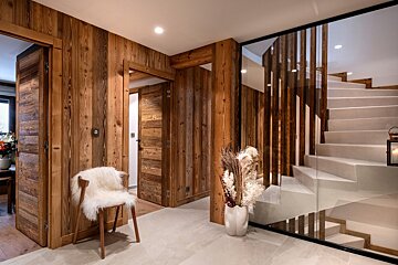 A staircase with a vase of dried flowers on the floor