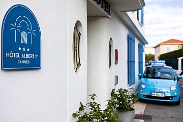 A blue car is parked in front of the hotel albert cannes