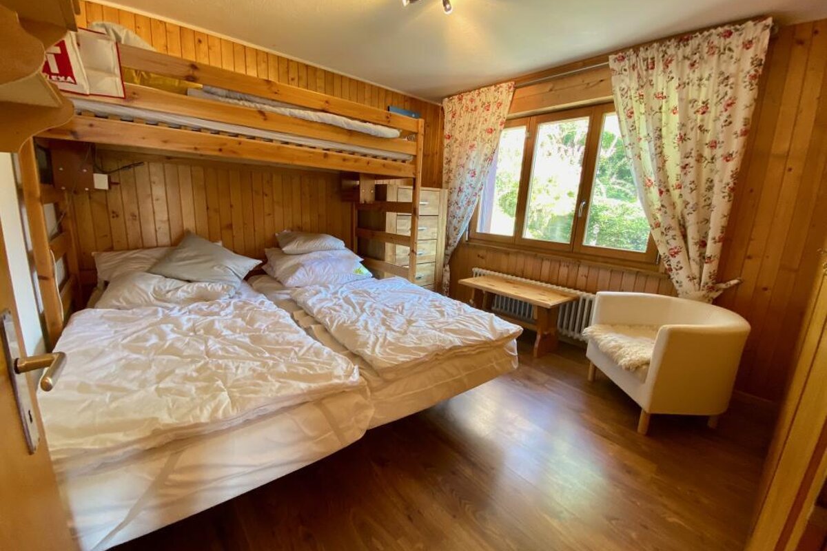 A bedroom with a bunk bed and a chair