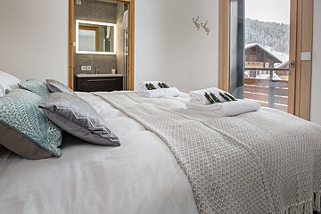 A bed with white sheets and pillows in a hotel room