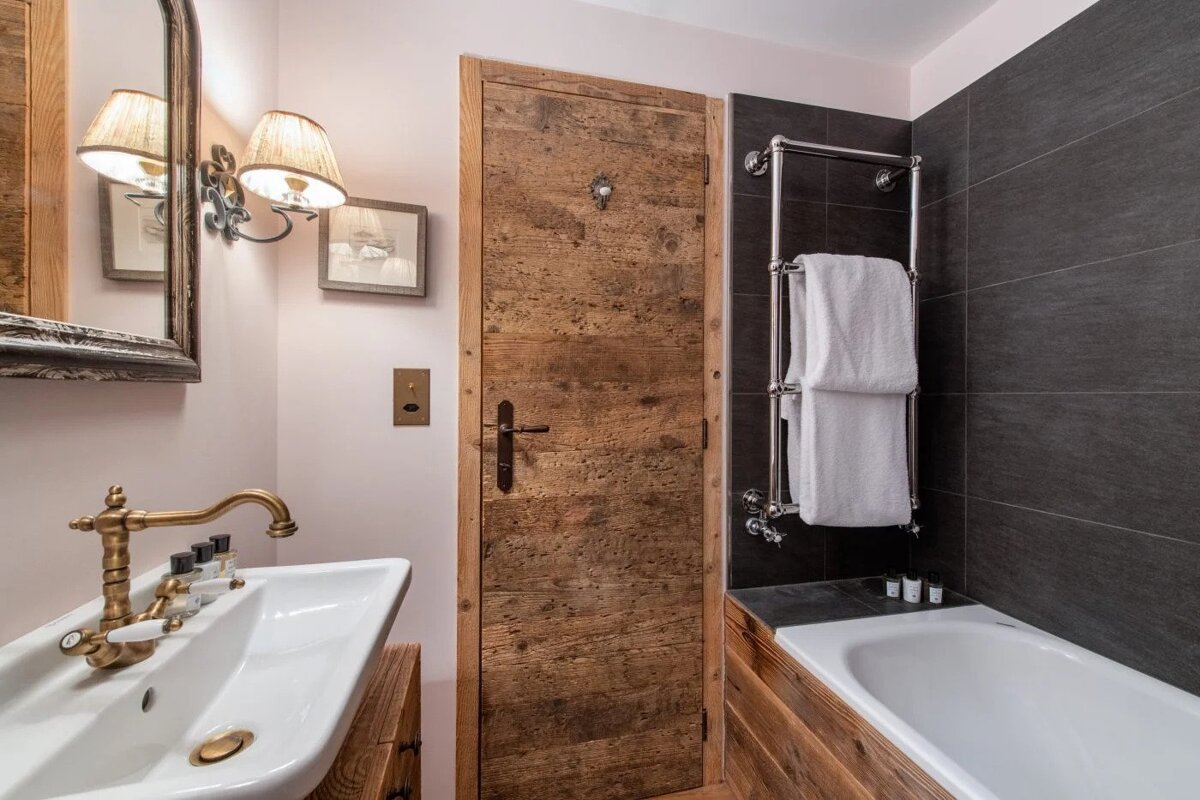 A bathroom with a wooden door and a bathtub