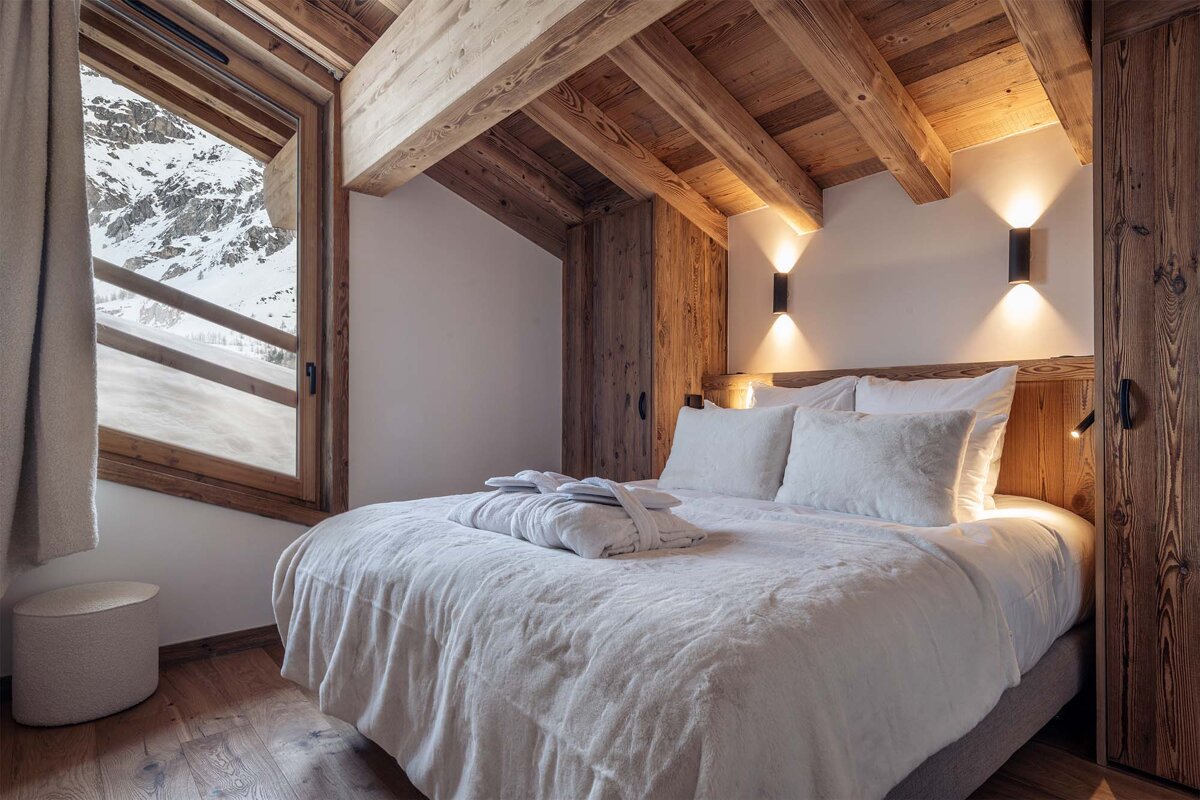 A bed with white sheets and pillows in a wooden room