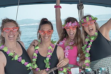 Four women wearing lei and sunglasses on a boat