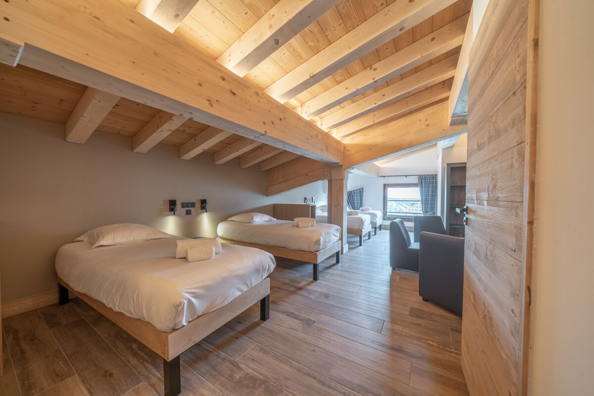 A bedroom with a wooden ceiling and three beds