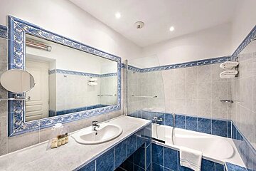 A bathroom with blue and white tiles and a large mirror