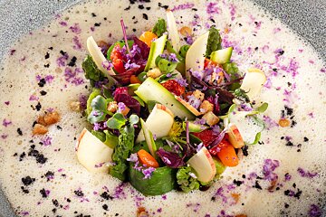 A close up of a salad with purple flowers on top