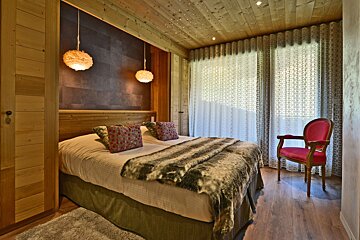 A bedroom with a large bed and a chair