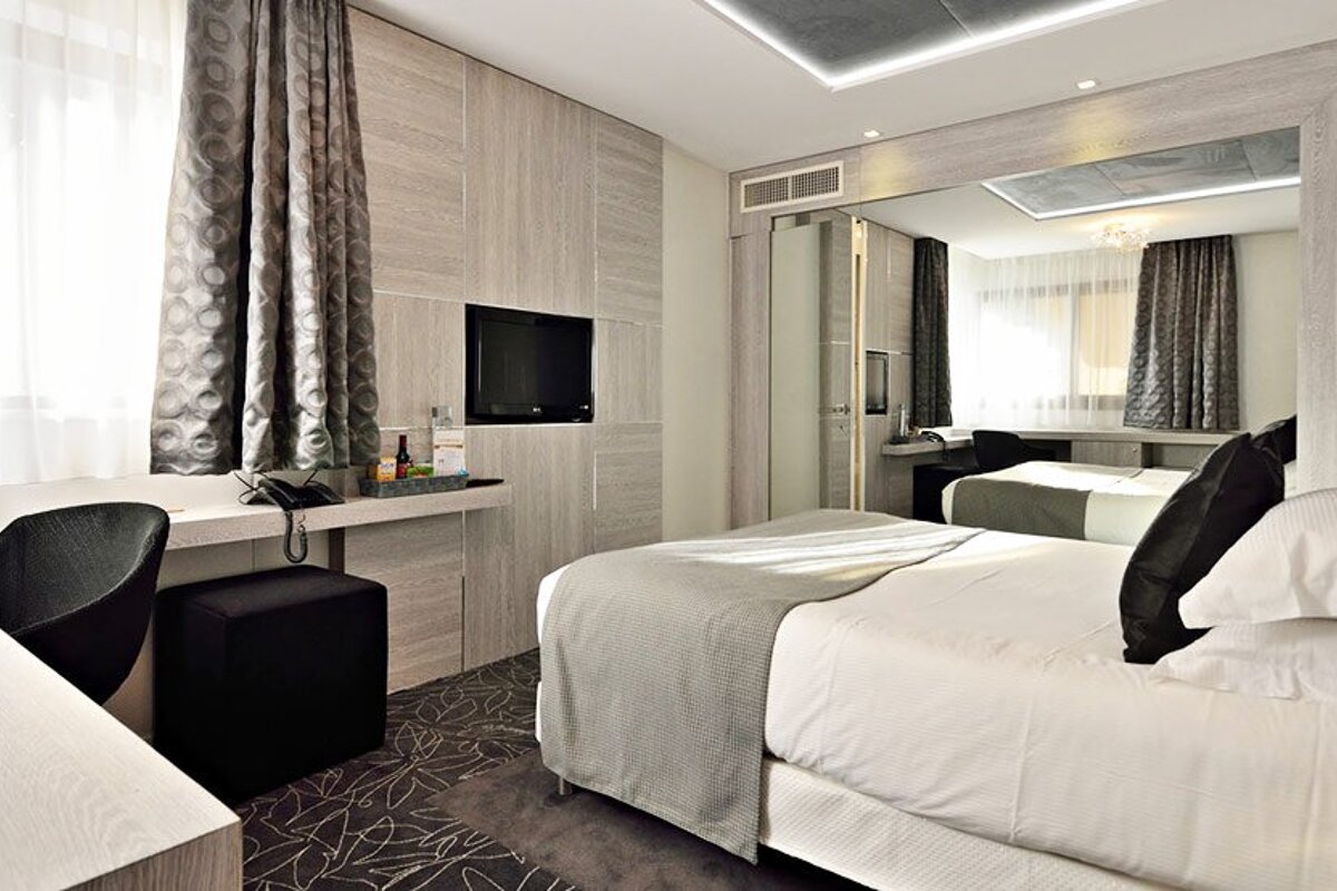 A hotel room with two beds and a flat screen tv