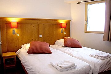 A bedroom with two beds and two lamps on the wall