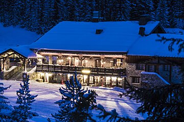 A snowy house with a sign that says ' l' ermitage ' on it
