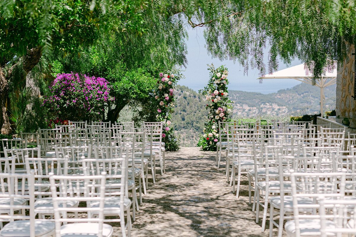 Rows of white chairs are set up for a wedding ceremony