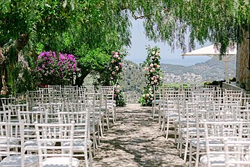 Rows of white chairs are set up for a wedding ceremony