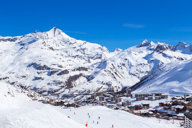Skiers on a snowy slope with mountains in the background