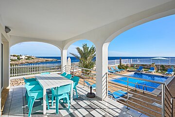 A balcony with a table and chairs overlooking a swimming pool