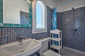 A bathroom with blue tiles and a blue shower curtain