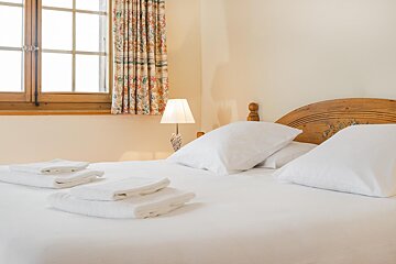 A bed with white sheets and pillows in a bedroom