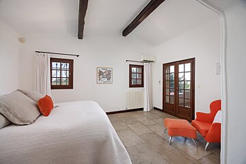 A bedroom with a bed a chair and a picture on the wall