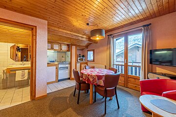 A living room with a table and chairs and a flat screen tv