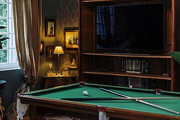 A pool table in front of a flat screen tv